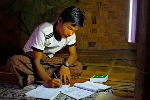 緬甸少年在菩提禪修機構捐贈的太陽能照明燈下學習