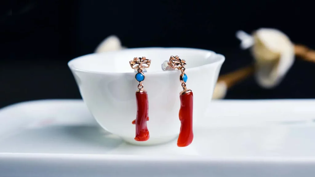 Earrings made of red coral, hanging on the edge of the bowl