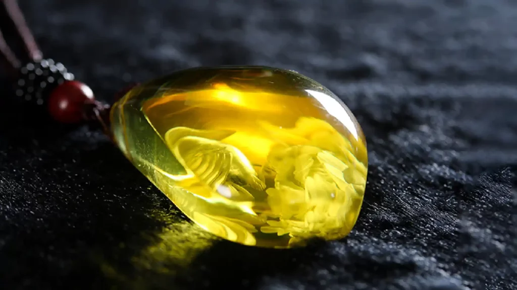 打磨成水滴狀的琥珀,發出黃色透亮光澤,琥珀內有凝固的金蘭花