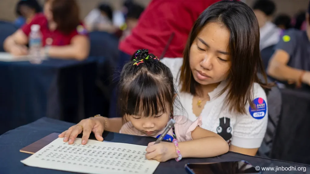 A mother and her child focused on hand-copying the Heart Mantra of Earth Store Bodhisattva.  